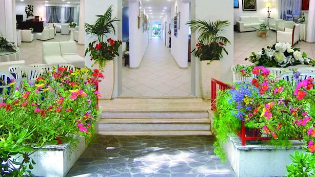 A hotel lobby with a central staircase, seating areas, and potted plants. - Noi Due Hotel (Rimini)