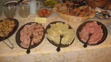 A buffet table with various food items including sliced meats, cheeses, and bread.