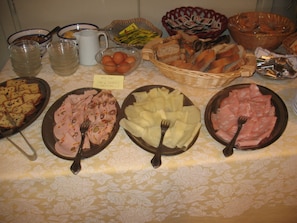 A buffet table with various food items including sliced meats, cheeses, and bread. - Hotel Monterosa (Ameno)