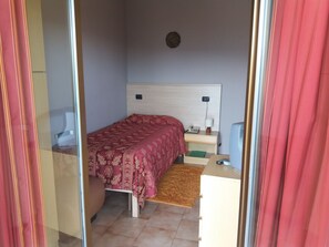 A bedroom with a bed, bedside table, lamp, and a television. - Hotel Monterosa (Ameno)
