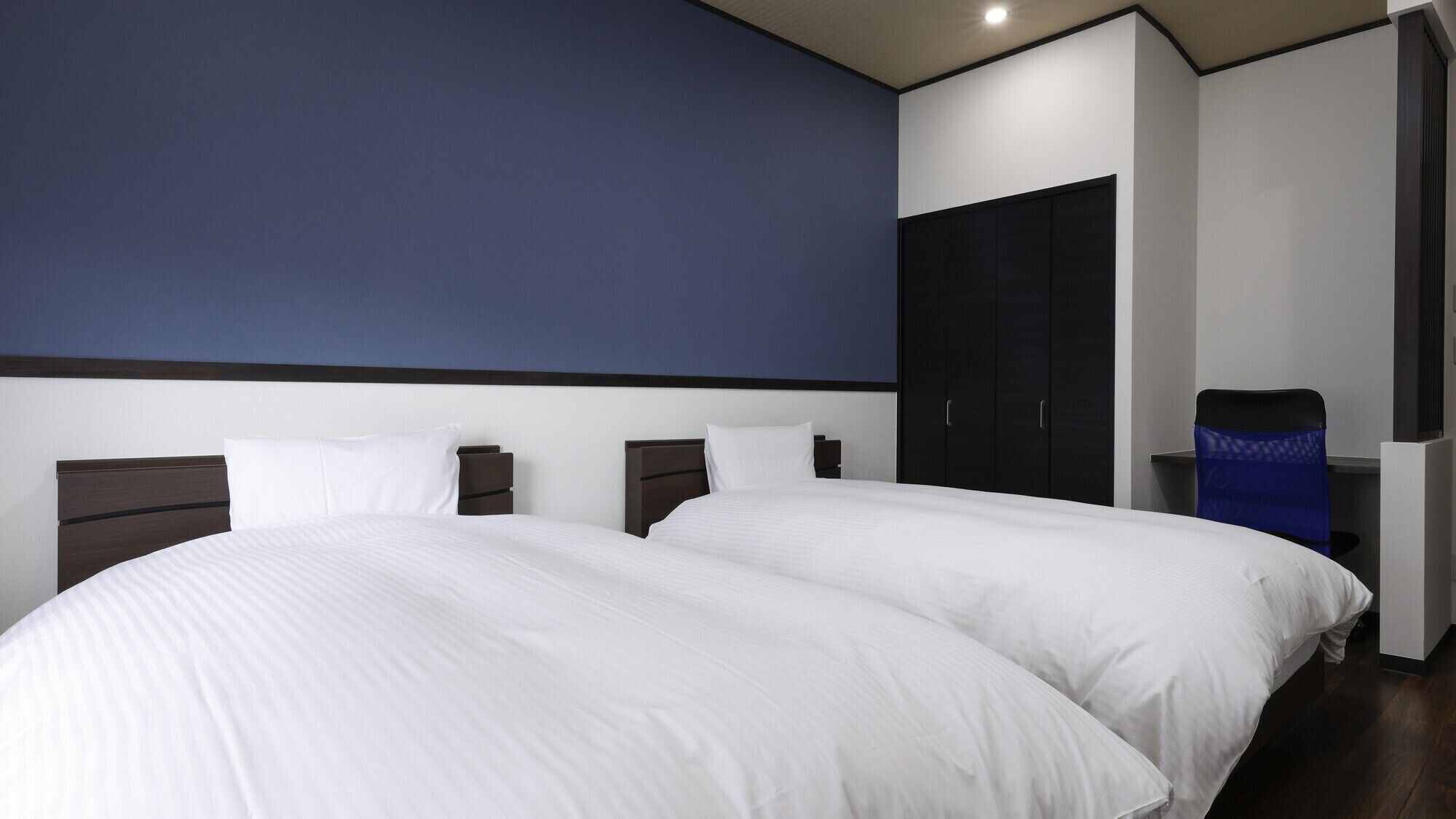 A hotel room with a large bed, a wardrobe, and a desk.