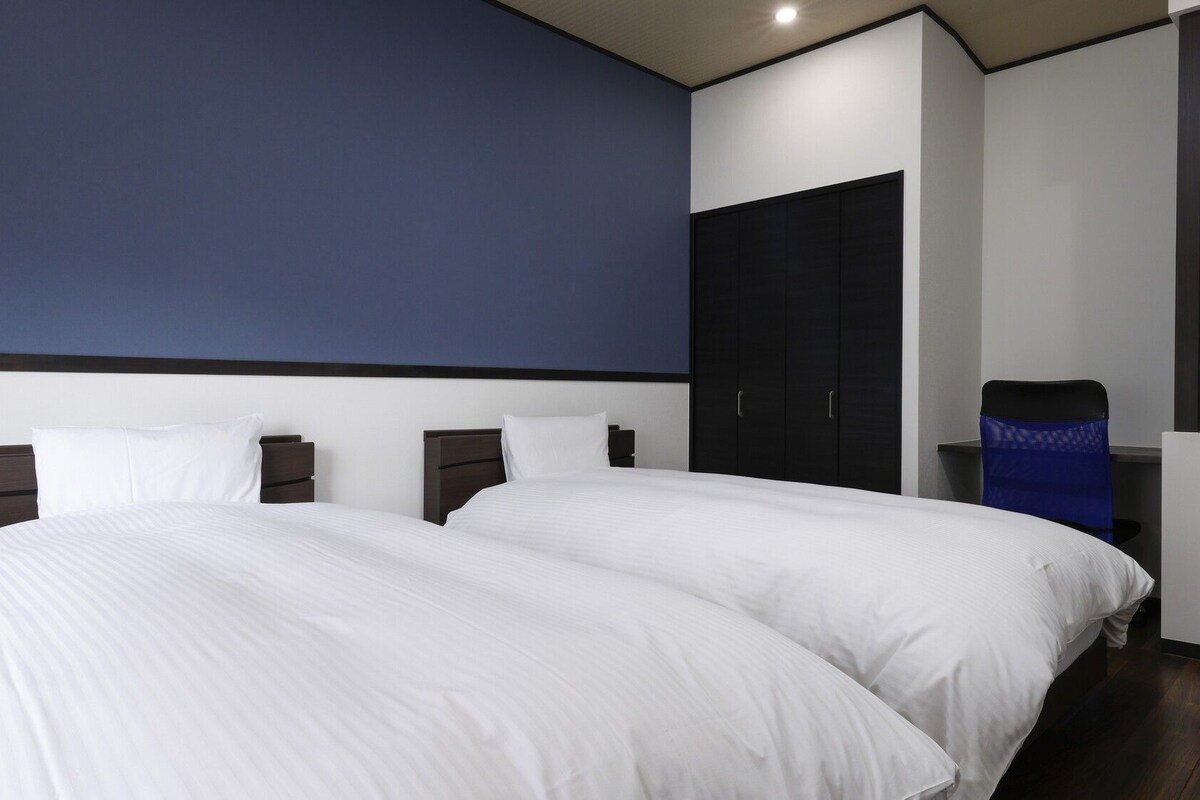 A hotel room with a large bed, a wardrobe, and a desk.