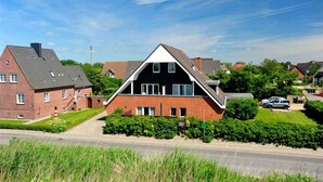 A residential building with a modern design, featuring a prominent triangular roof and a brick facade. - Apartment 5 (ID 171), Germany (Sankt Peter-Ording)