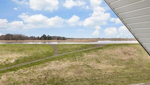 A view of a grassy field with a pond and a path leading to it. - Apartment 5 (ID 171), Germany (Sankt Peter-Ording)