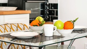 A breakfast setting with a glass table, bowls of fruit, a white mug, and a toaster in the background. - Danezis City Stars (Rhodes)
