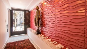 A hallway with a statue, a textured wall, and a patterned rug. - Danezis City Stars (Rhodes)
