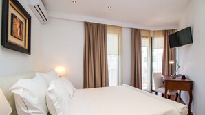 A hotel room with a bed, a desk, a chair, a TV, and a window with curtains. - Danezis City Stars (Rhodes)