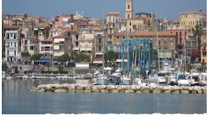 Un poble costaner amb un port esportiu, que presenta una barreja d'edificis residencials, una torre destacada i un moll de pedra.