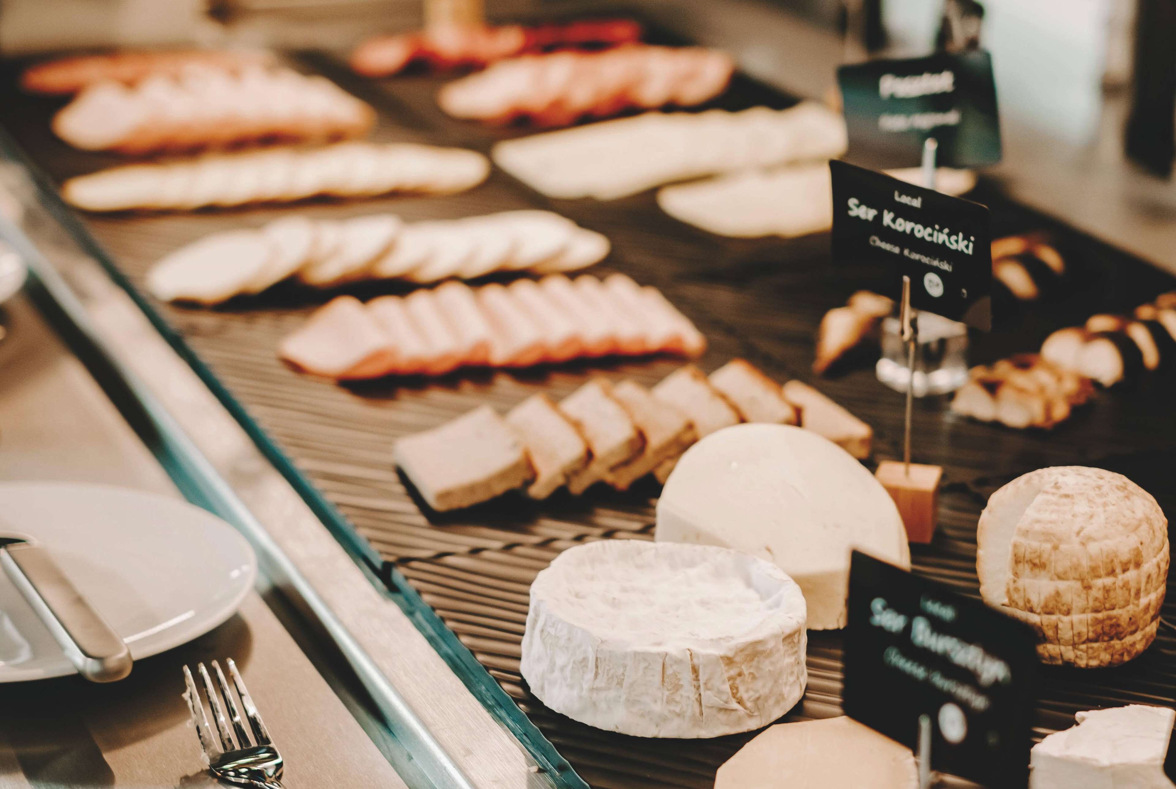 A cheese display with various types of cheese and labels indicating names and prices.