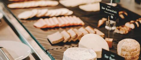 A cheese display with various types of cheese and labels indicating names and prices.