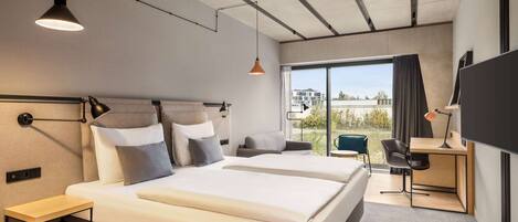 A modern hotel room with a large bed, two bedside tables, a desk with a chair, and a TV.