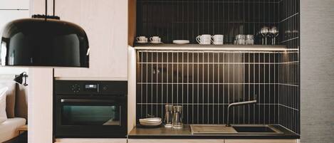 A compact kitchen with a black oven, a sink, and a countertop with various kitchenware.