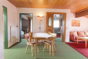 Un comedor con una mesa y sillas de madera, una alfombra roja y un sofá rojo.