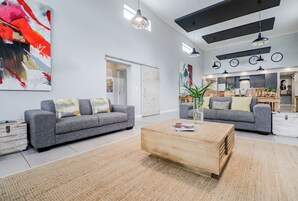 A modern living room with two grey sofas, a wooden coffee table, and a large abstract painting.