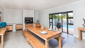 Une cuisine moderne avec des meubles en bois, un four encastré et une grande fenêtre donnant sur une piscine.