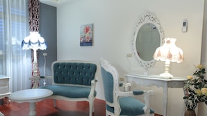 Una habitación con un sofá azul, una mesa blanca, un espejo y una lámpara.