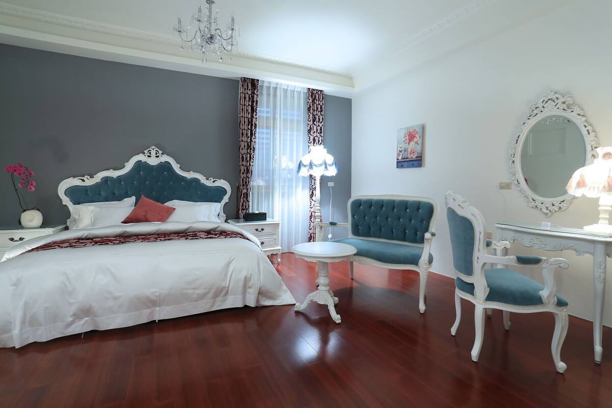 Un dormitorio con una cama grande, una silla, un escritorio y un espejo.