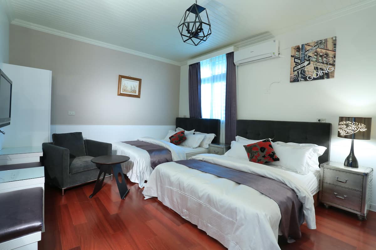 Una habitación de hotel con dos camas, un escritorio, una silla y un televisor.