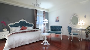 Un dormitorio con cama, una silla, una mesa, un espejo y una araña.