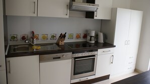 A modern kitchen with white cabinets, stainless steel appliances, and a coffee maker. - Moor Apartment (Singen)