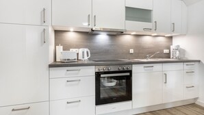 A modern kitchen with white cabinets, a built-in oven, a coffee maker, and a toaster. - Apartment EC right (ID 137) - House Everschop (Sankt Peter-Ording)