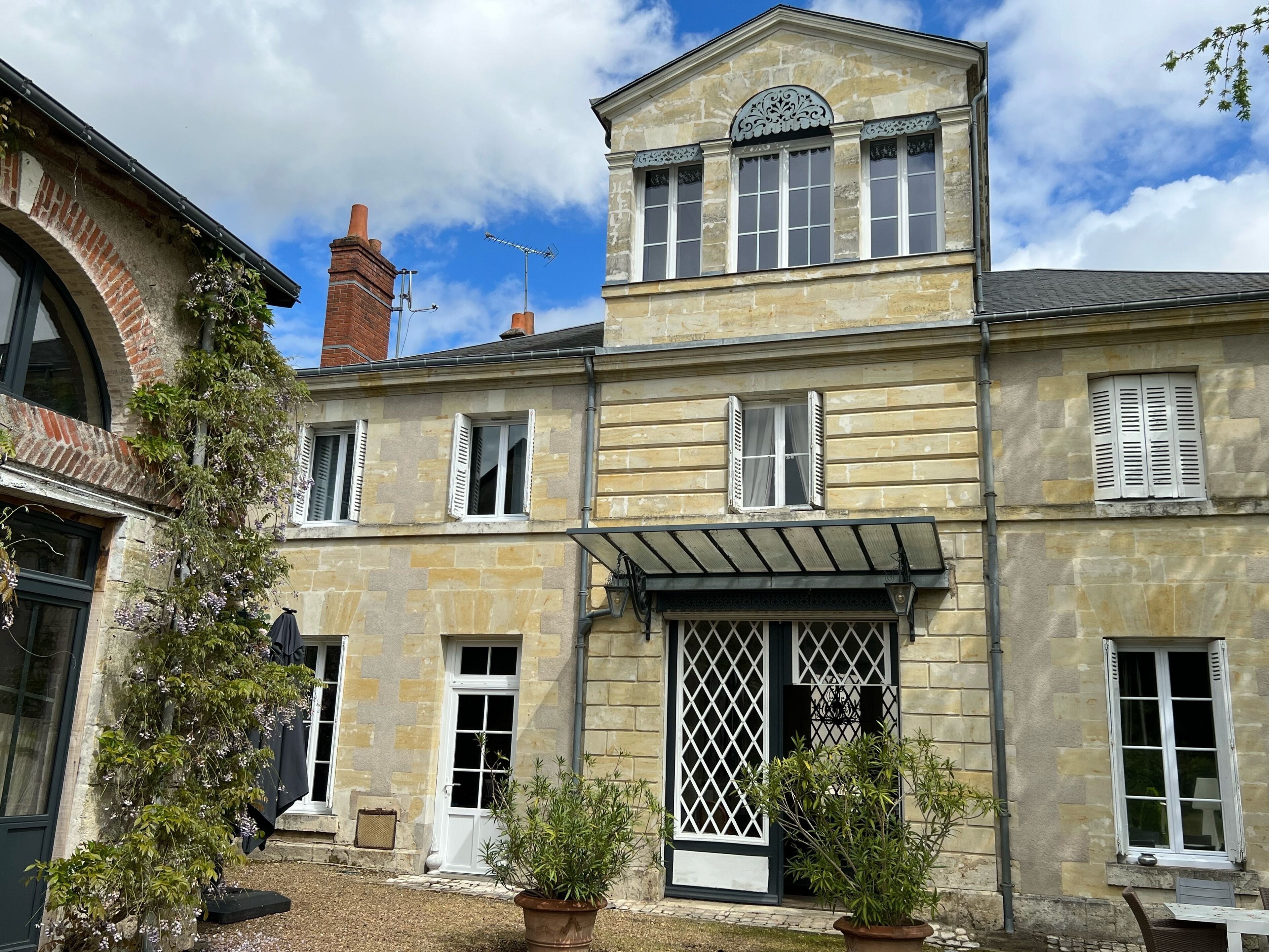 A two-story stone building with a central entrance, a small balcony, and a chimney.