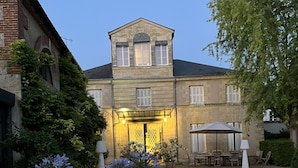 Une cour avec un bâtiment en pierre, des sièges en plein air et des plantes en pot.