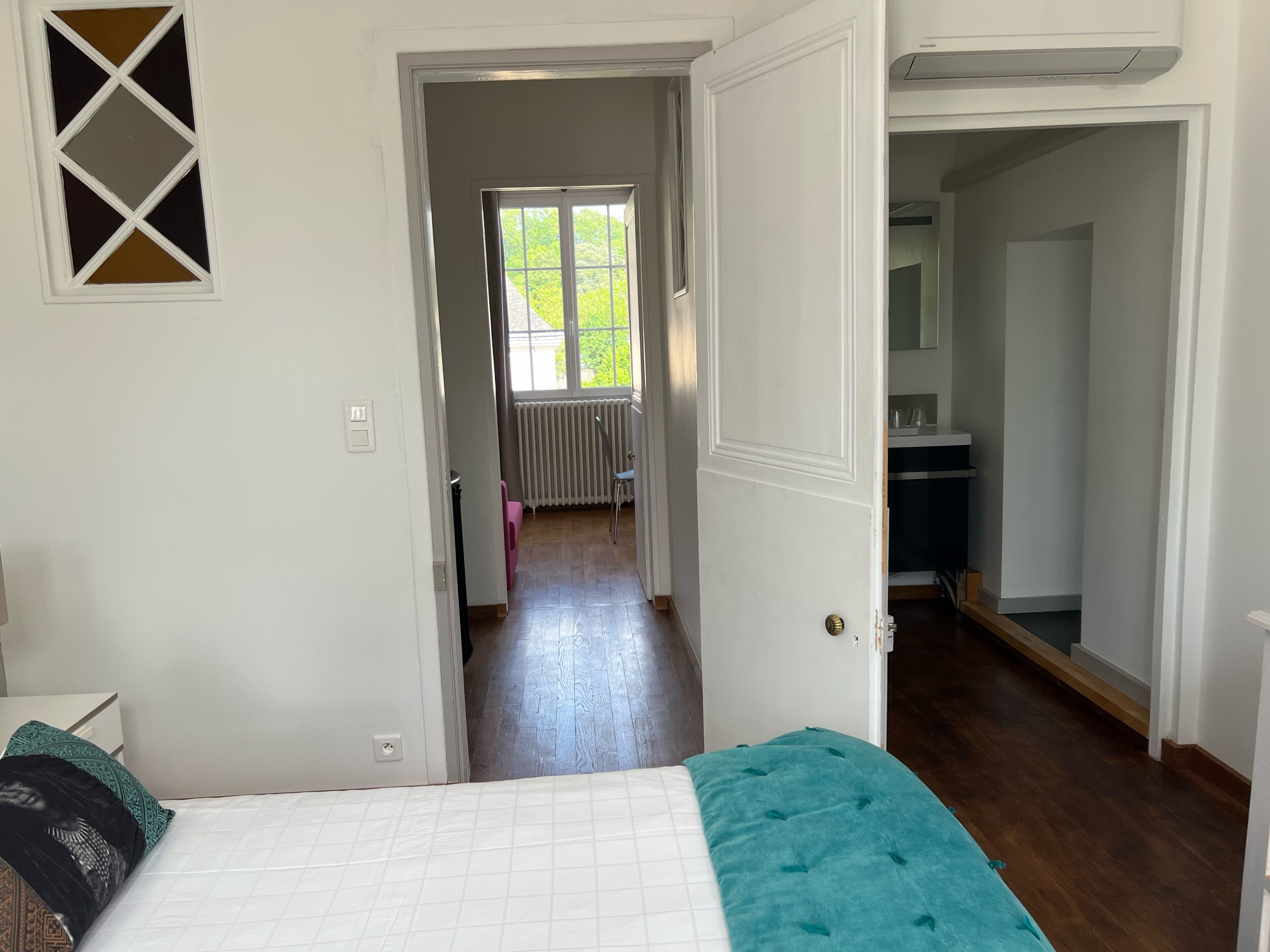 Un dormitorio con cama, ventana y puerta que da a un pasillo.