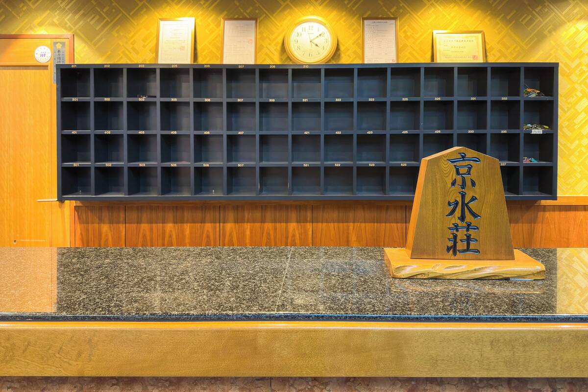 Un comptoir d’accueil avec une horloge, des certificats encadrés et une plaque en bois portant des caractères chinois.