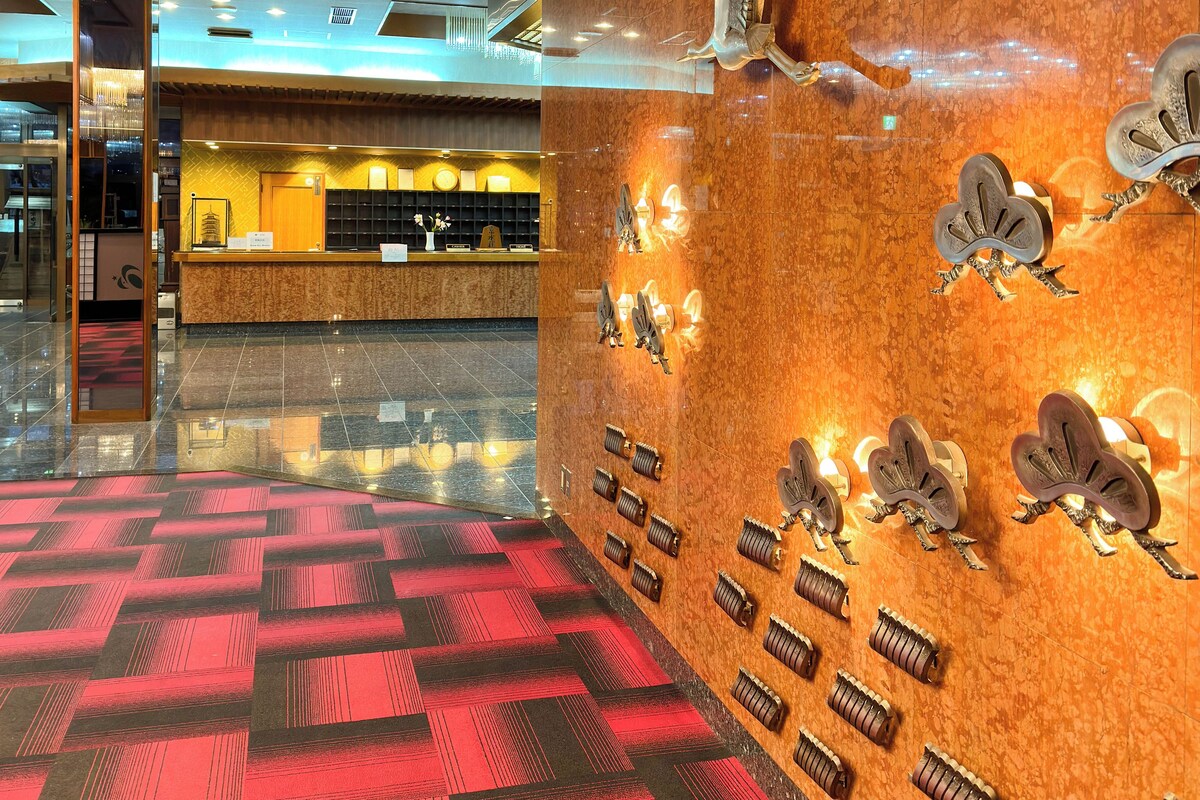 Eine Lobby mit Teppichmuster, einem Empfangstresen und Wandskulpturen von Vögeln.