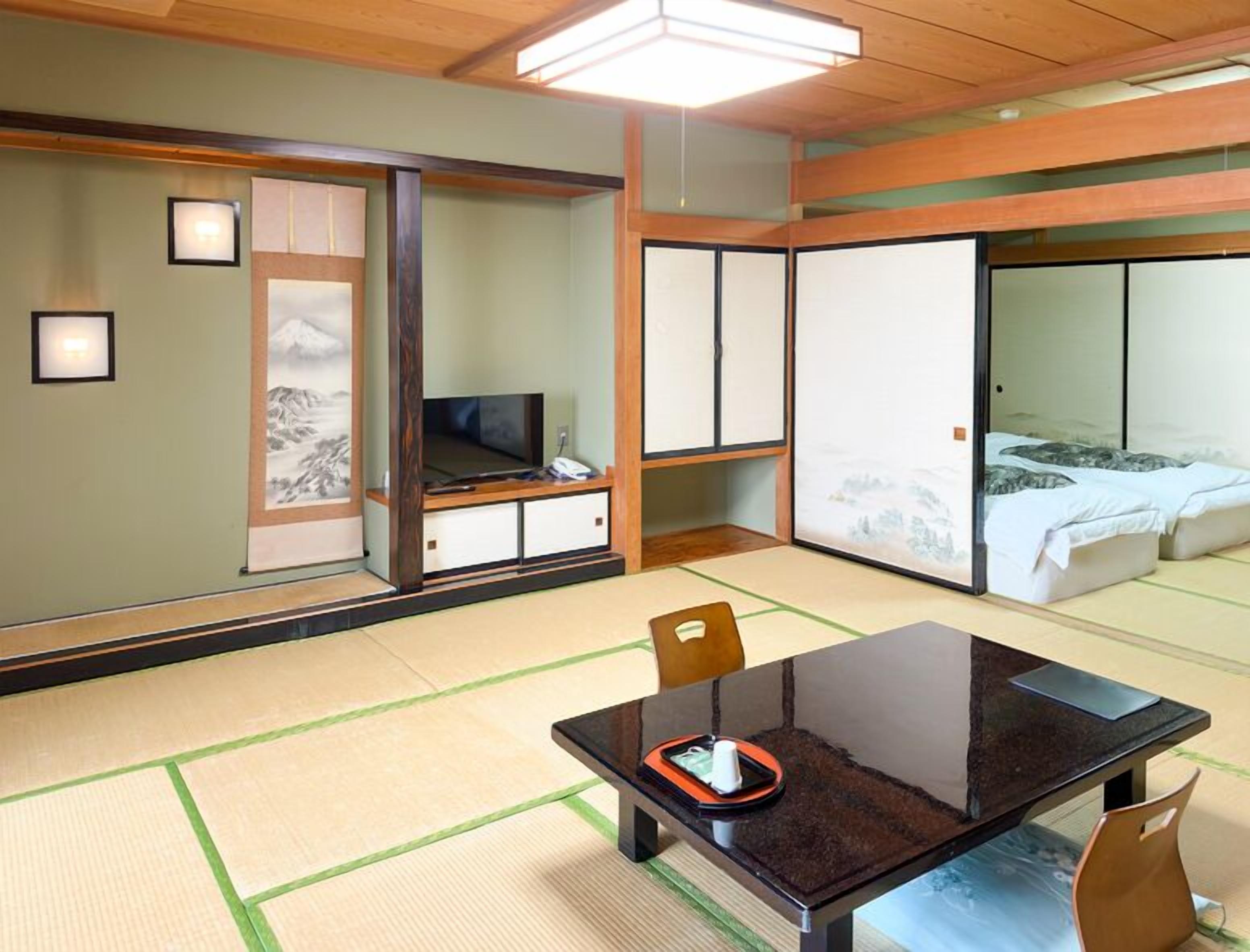 Una habitació tradicional japonesa amb sòls de tatami, una taula baixa amb safata i un llit amb llits de tipus futón.