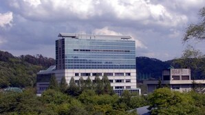 A modern multi-story building with a glass facade, surrounded by trees and hills. - TAS Park Hotel Nagai (Nagai)