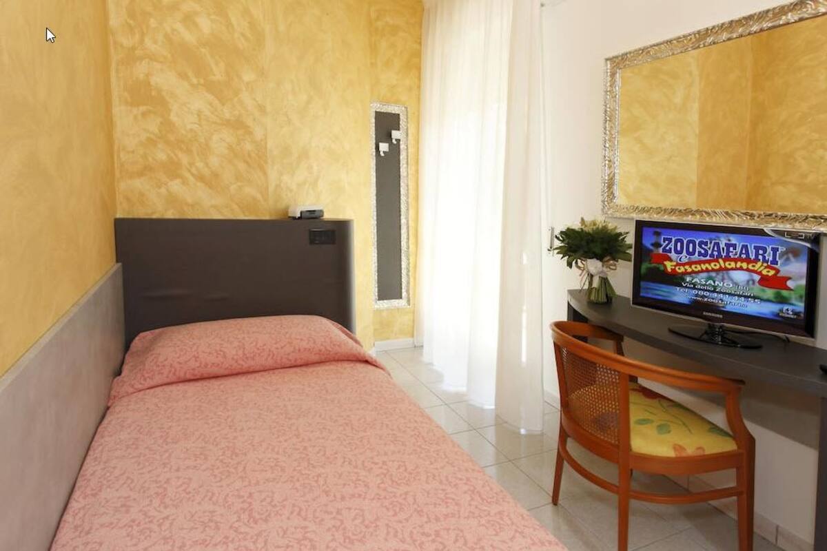 Een hotelkamer met een bed, een bureau met een televisie en een stoel.