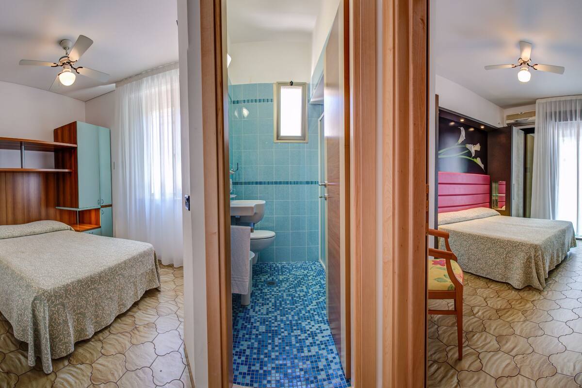 Een hotelkamer met twee bedden, een badkamer en een douche.