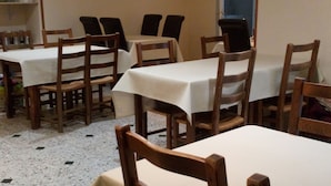 Un comedor con mesas y sillas, suelo de baldosas y una ventana.