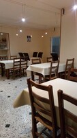 Un comedor con mesas y sillas, suelo de baldosas y una ventana.