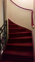 Una escalera con peldaños alfombrados en rojo y barandilla morada.