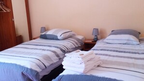Una habitación de hotel con dos camas individuales, un armario de madera y una alfombra roja.