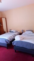 Una habitación de hotel con dos camas individuales, un armario de madera y una alfombra roja.