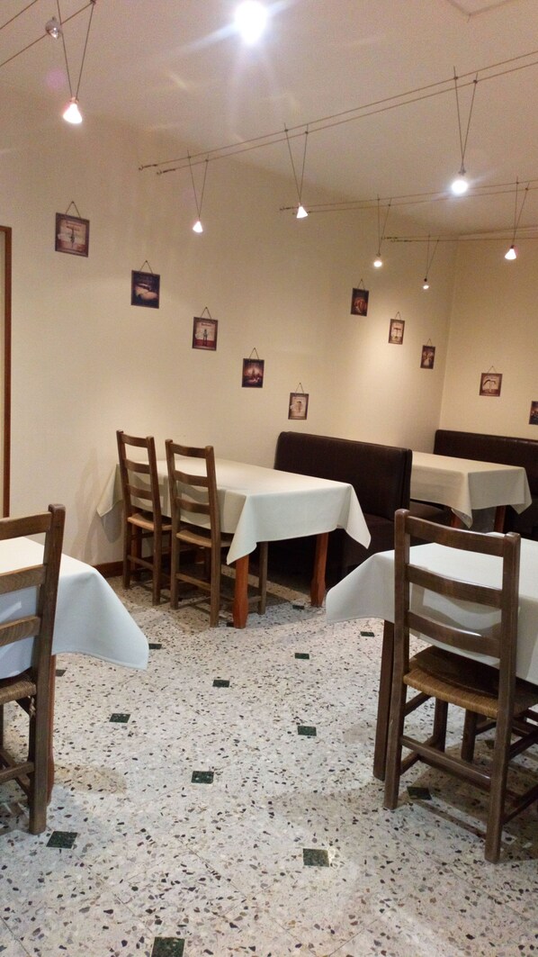 A restaurant interior with wooden chairs and tables, a speckled floor, and framed pictures on the walls. - La Roseraie (Amberieux-en-Dombes)
