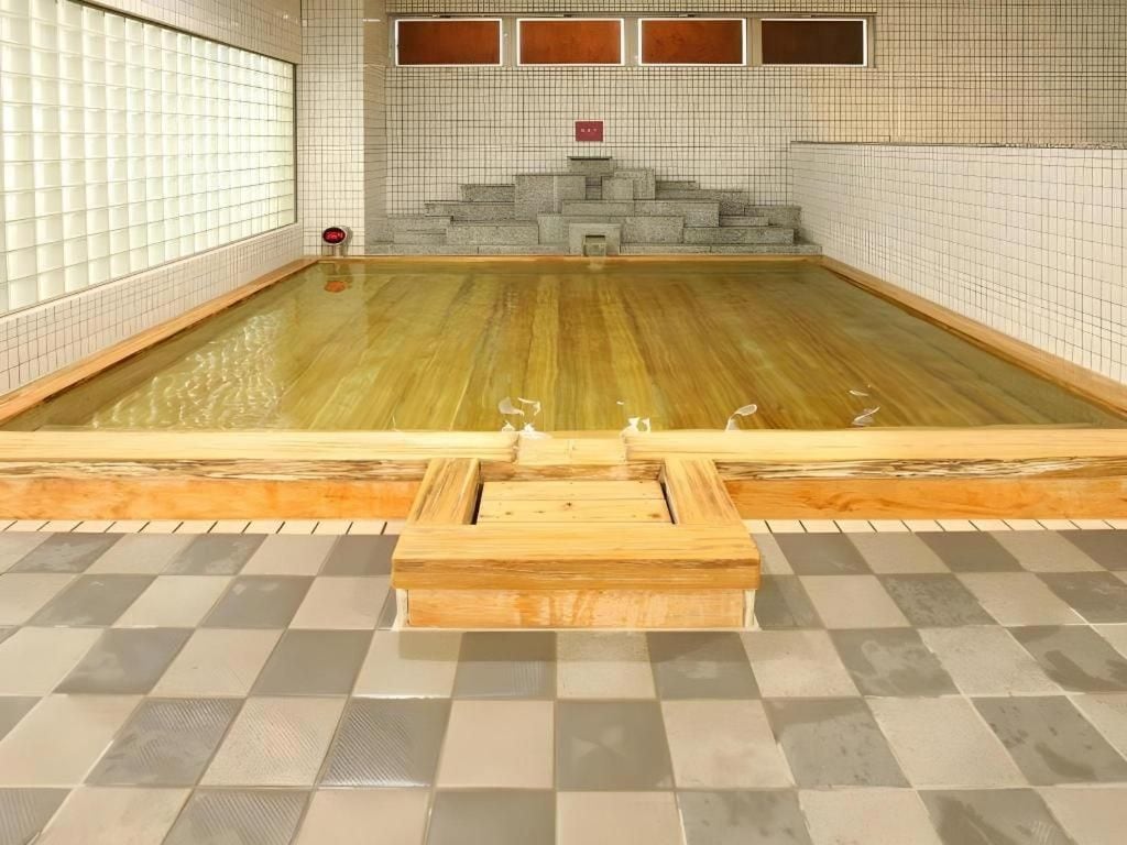 A swimming pool with a checkered floor, tiled walls, and a wooden structure in the center.