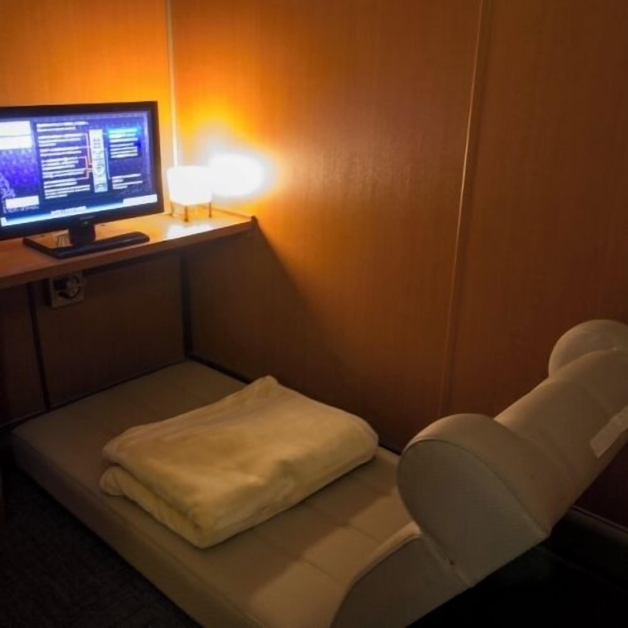 Een hotelkamer met een bed, een bureau met een computer en een lamp.