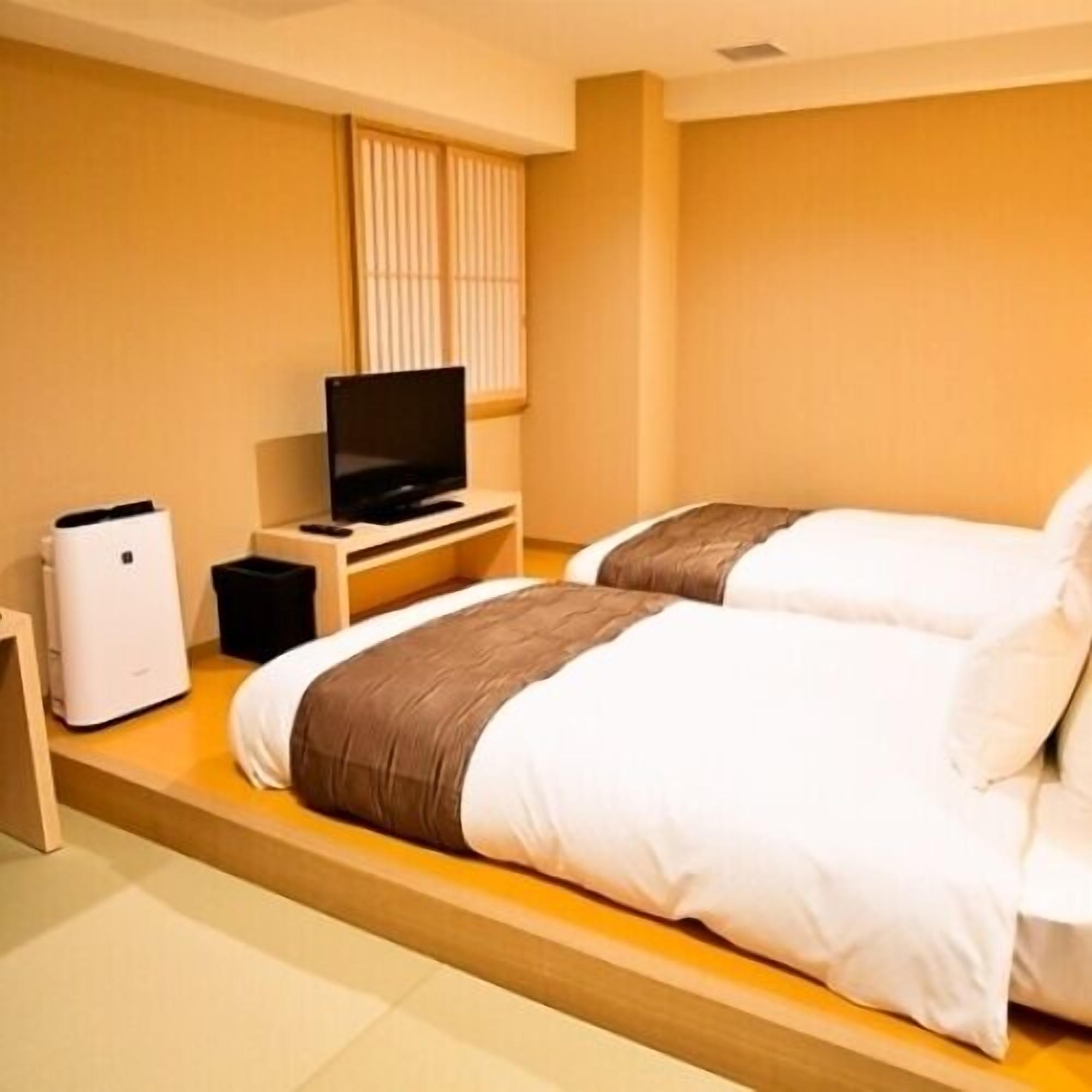 Una habitación de hotel con dos camas, un televisor y un calentador.