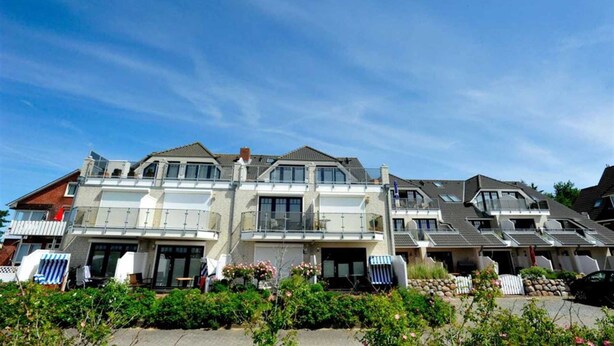 A multi-story residential building with balconies, large windows, and a well-maintained garden area. - Apartment 6 "Schröder" (ID 045) - Haus Zum Böhler Strand 10 (Sankt Peter-Ording)
