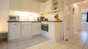 A modern kitchen with white cabinets, a microwave, a dishwasher, and a stove. - Apartment 6 "Schröder" (ID 045) - Haus Zum Böhler Strand 10 (Sankt Peter-Ording)