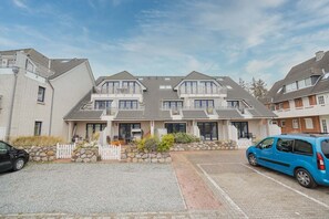 Reihenweise zweigeschossige Häuser mit Kiesauffahrt und Parkplatz.