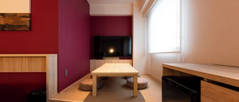 Una sala de estar moderna con una mesa de madera, un sofá negro y un televisor de pantalla plana.