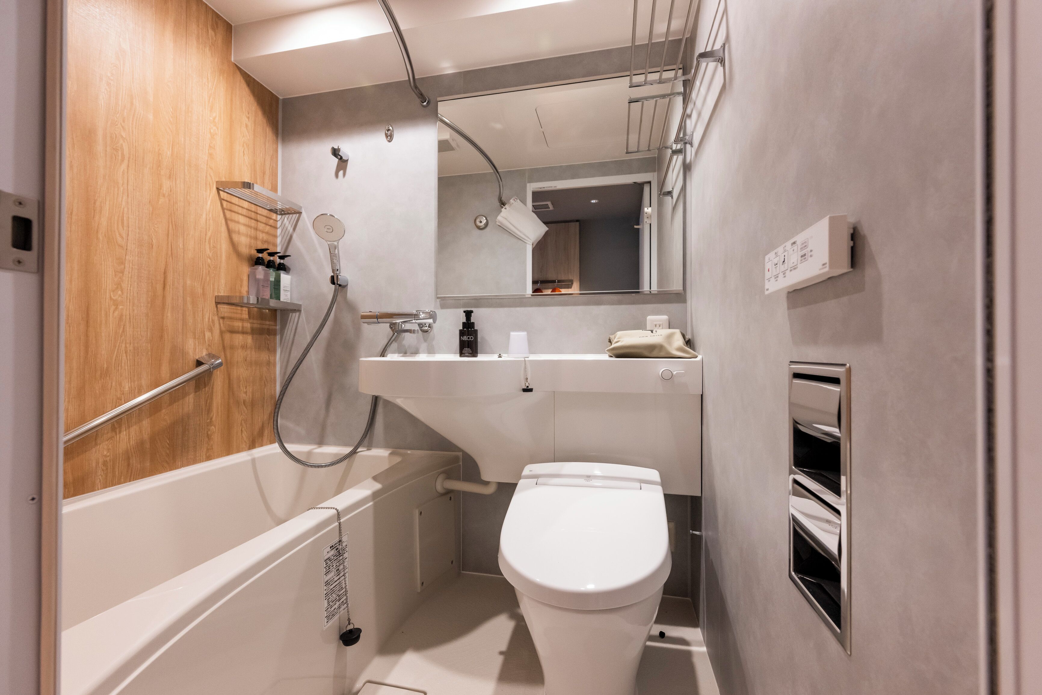 A modern bathroom with a bathtub, toilet, and a vanity with a mirror.