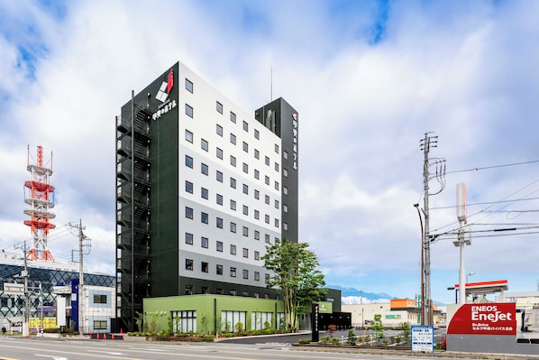 A modern hotel with a prominent entrance, multiple floors, and a green facade. - Kaino Hotel (Kofu)
