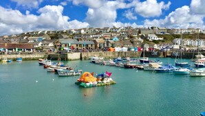 A harbor with boats, a colorful fish-shaped float, and buildings in the background. - Tresowes Green Cottage (Helston)